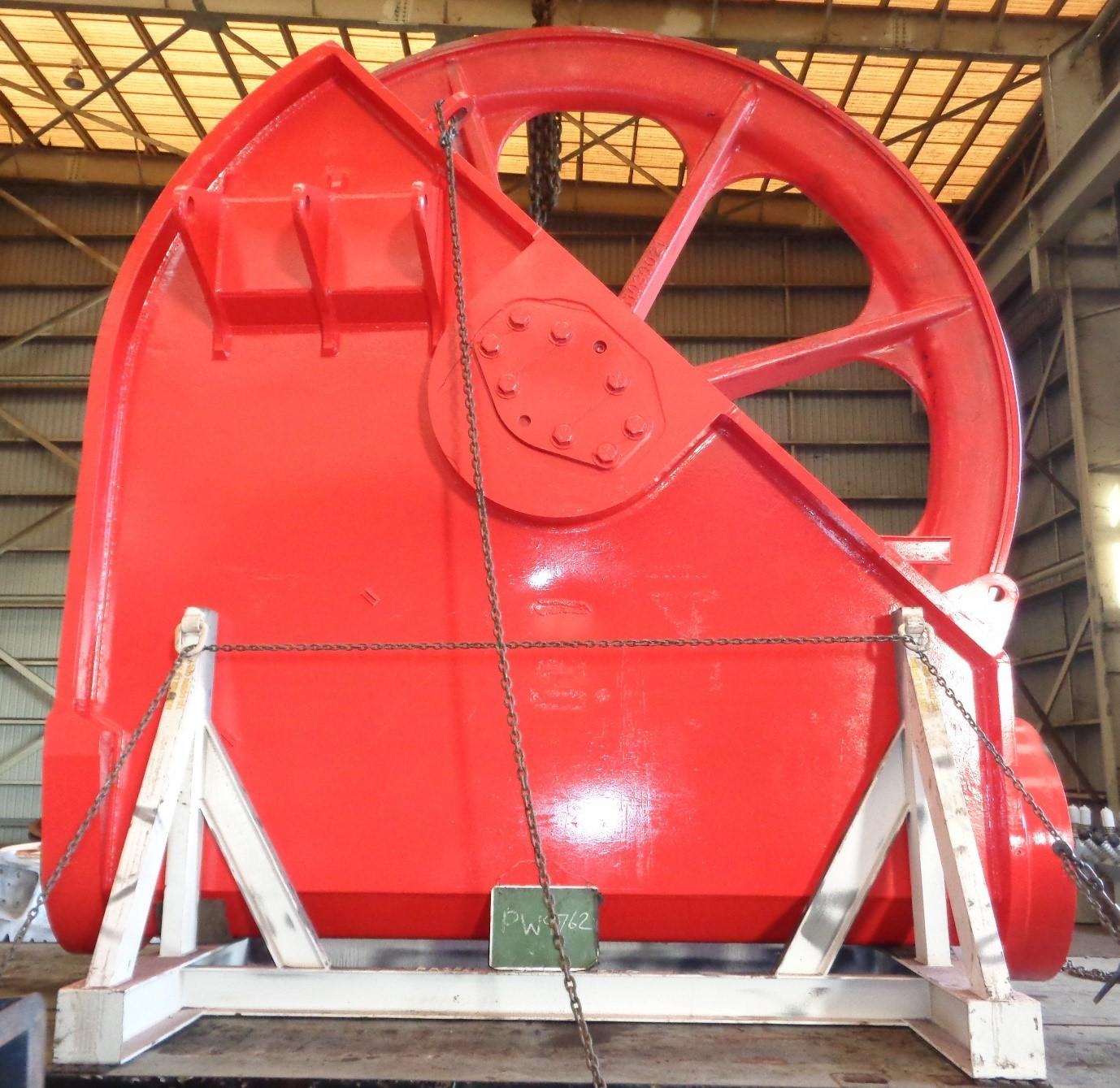 Large dragline sheave wheel finished in fresh red industrial coating, on stands in the paint bay